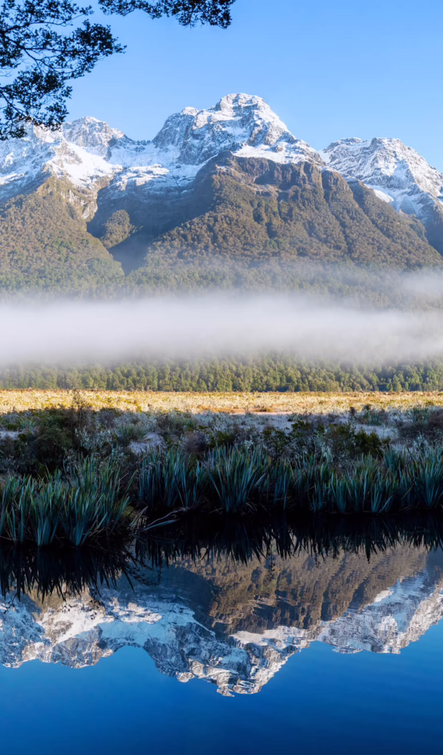 Snow-covered mountains reflected in the Mirror Lakes near Milford Sound, New Zealand