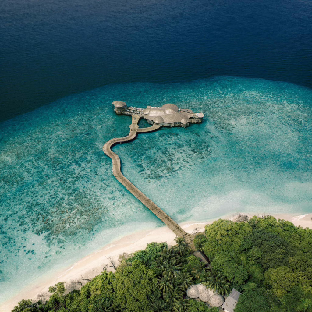 Aerial view of overwater villas and coral reef at Soneva Fushi, Maldives