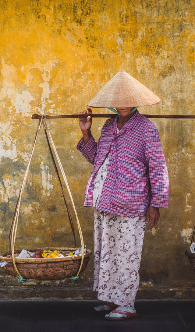 Street vendor carrying baskets on a shoulder pole in Vietnam